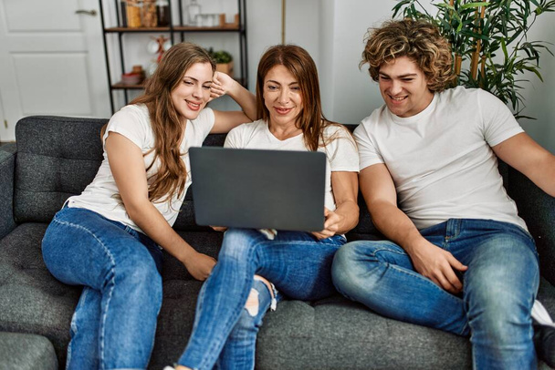 Mother and couple using laptop sitting on sofa at home - Foto, imagen