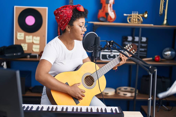 アフリカ系アメリカ人女性ミュージシャンの歌が音楽スタジオでクラシックギターを演奏 - 写真・画像