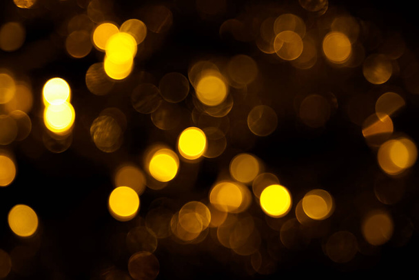 Abstract gold bokeh on black background. Defocused yellow lights, abstract texture. - Fotó, kép