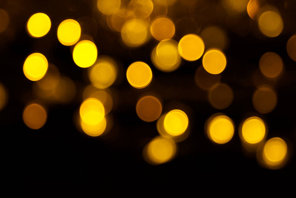 Abstract gold bokeh on black background. Defocused yellow lights, abstract texture. - Photo, Image