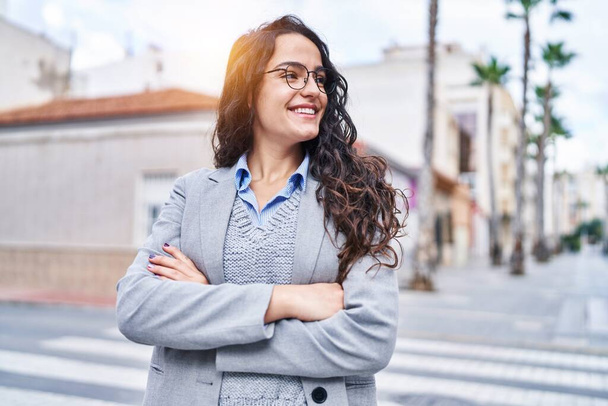 Молода іспаномовна жінка-виконавчий усміхнений впевнений, що стоїть з руками перетнув жест на вулиці
 - Фото, зображення