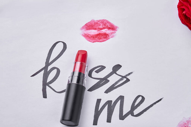 Red lipstick with kiss me writing and lips imprint. Close up top view. - Foto, Imagem