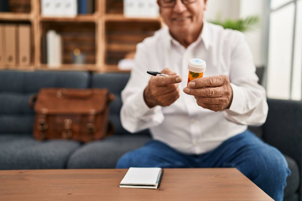Starší muž psycholog s úsměvem sebevědomě předepisovat pilulky v psychologickém centru - Fotografie, Obrázek