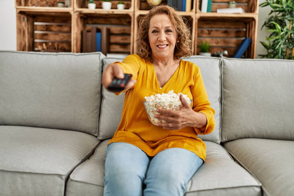 Middle age caucasian woman watching movie sitting on the sofa at home. - Foto, Imagen
