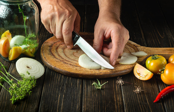 Готуємо мариновані овочі в банці. Кухар розрізає цибулю ножем на обробній дошці кухні. Крупним планом руки шеф-кухаря під час роботи
 - Фото, зображення