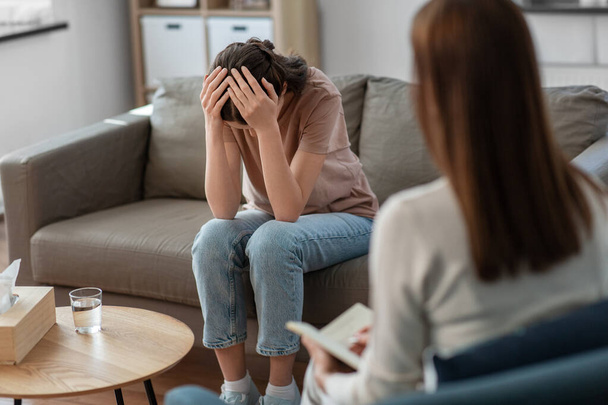 psychology, mental health and people concept - stressed young woman patient and psychologist at psychotherapy session - Photo, Image