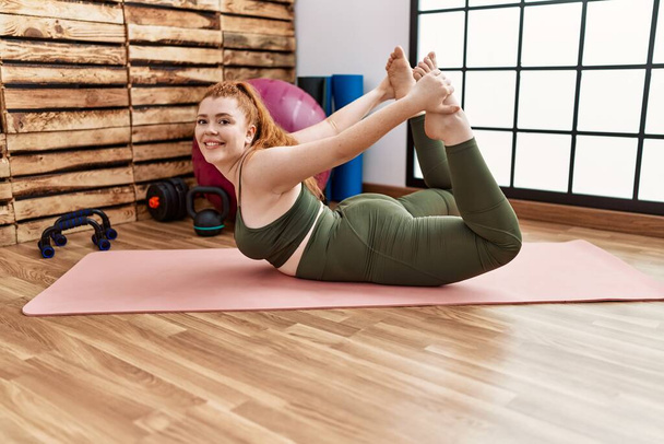 Mladý ryšavý žena usměvavý jistý stretching na sportovní centrum - Fotografie, Obrázek
