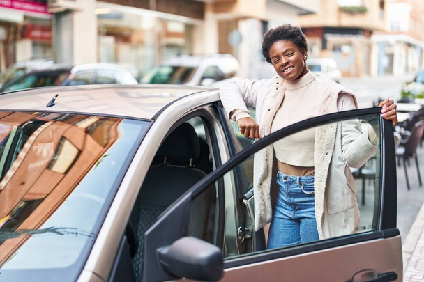 Африканская американка улыбается уверенно открывая дверь машины на улице - Фото, изображение