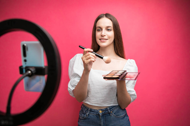 Beauty blogger recording makeup tutorial on pink background. High quality photo - Fotó, kép