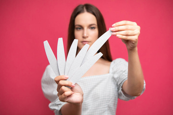 picture of young girl holding nail files and choosing one of them. High quality photo - Foto, Bild