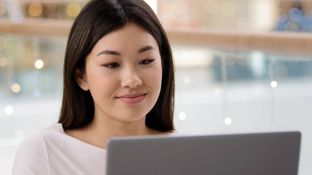 Portrait asian female face looking at laptop satisfied girl woman freelancer boss worker manager businesswoman typing computer using shopping app service watching video online on website browsing net - Photo, Image