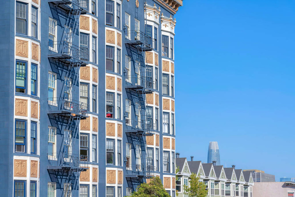 Багатоповерхова багатоповерхова житлова будівля і складні таунхауси в Сан-Франциско, Каліфорнія. Зліва є квартира з синім і золотим екстер'єром і вікнами бухти поруч з міськими будинками з ямними дахами.. - Фото, зображення