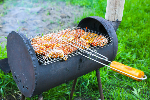 Chicken on grill outdoors. Barbecue on fire in summer. Good time. Cooking meat in the nature. - Photo, Image