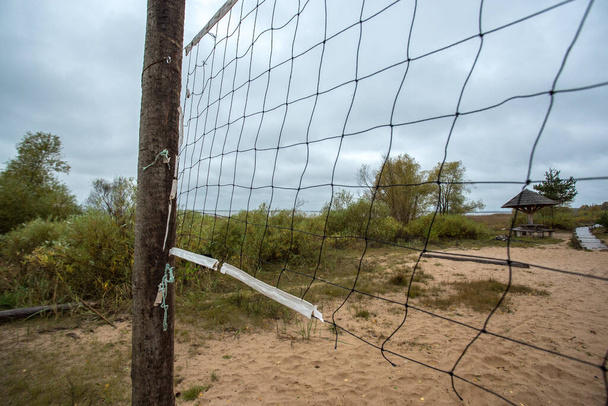 Ένα θραύσμα από ένα παλιό δίχτυ βόλεϊ, σε μια μοναχική παραλία δίπλα σε μια λίμνη στη Λετονία. . Υψηλής ποιότητας φωτογραφία - Φωτογραφία, εικόνα