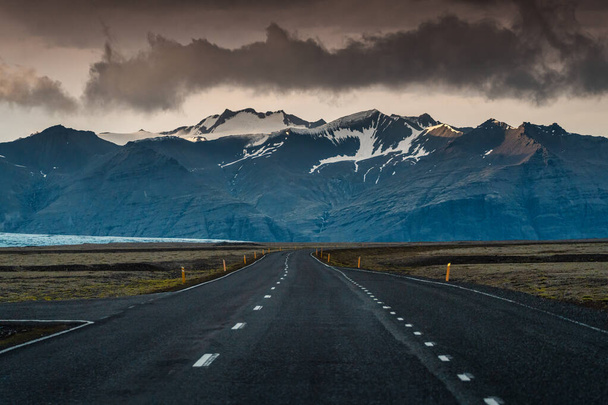 Драматична пряма асфальтна дорога з штормом через гори в похмурий день в Ісландії. - Фото, зображення