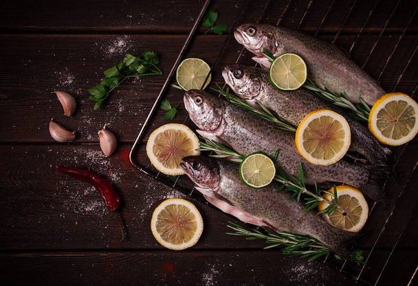 Raw rainbow trout, with lemon and herbs, on a wooden table, no people, - Photo, Image