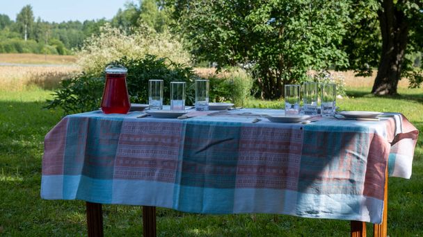 Prepare the country holiday lunch table. Juice cup with glasses. On a cotton tablecloth. - Zdjęcie, obraz