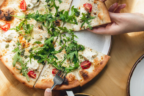 Detailní záběr, vegetariánská pizza s cherry rajčaty a rukolou na dřevěném stole, pohled shora. - Fotografie, Obrázek