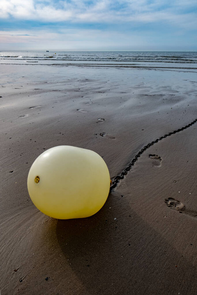 Bóia branca em uma corrente com reflexão sobre uma praia na maré baixa em Blankenberge, Bélgica. Foto de alta qualidade - Foto, Imagem