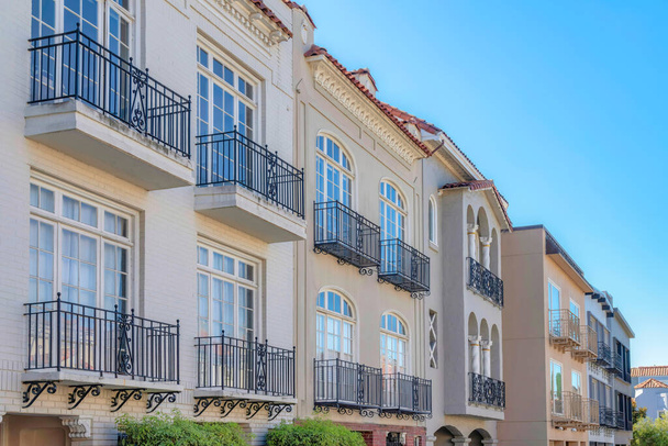 Row of mediterranean houses with wrought iron railings on its window balconies in San Francisco, CA. Facade side view of a residential buildings with stucco walls and bricks. - Foto, imagen