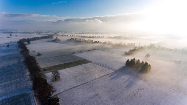 An aerial shot of snow-covered fields with sunlight on the right side - Photo, image