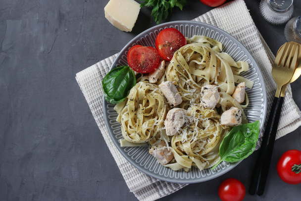 Tagliatelle pasta with chicken and cheese, served with cherry tomatoes and basil on dark gray background, Top view - Photo, image