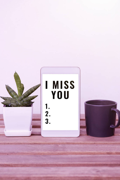 Writing displaying text I Miss You, Conceptual photo Feeling sad because you are not here anymore loving message Tablet With Important Information On Table With Plant And Cup Of Coffee. - 写真・画像