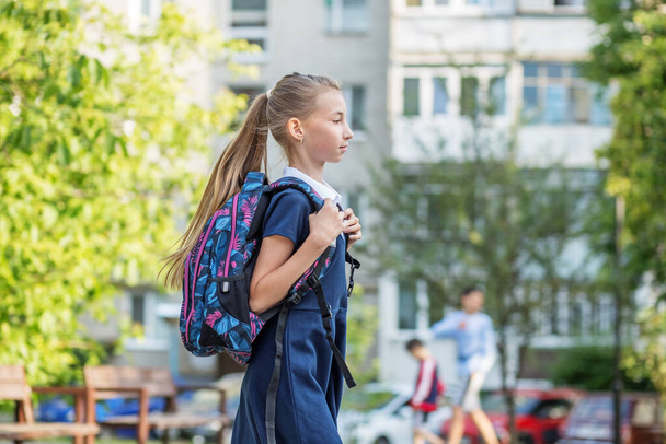 Krásná dospívající dívka s batohem chodí do školy. Koncept návratu do školy, vzdělávání a dětství - Fotografie, Obrázek