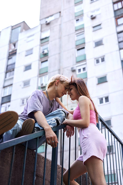 A lovely teenage couple is hugging and snuggling outside in an urban exterior surrounded by buildings and skyscrapers. - Foto, imagen