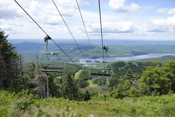 A panoramic view of Mont-Tremblant city with cable cars with a lake in the background on a sunny day - Fotoğraf, Görsel