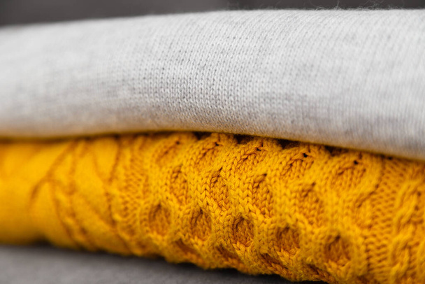 Knitted pullovers close up in trendy grey and yellow colors. Colors of the 2021 year. Stack of cozy knitted sweaters, winter concept. - Fotó, kép