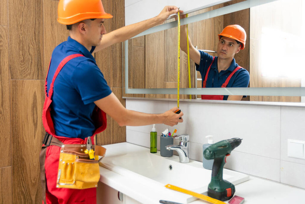 Pracovník instaluje zrcadlo v koupelně - Fotografie, Obrázek