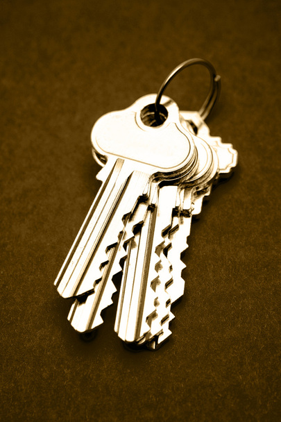 Куча ключей от дома на коричневом фоне
 - Фото, изображение