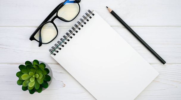 Office desk with blank notepad, glasses and pencil. Mockup notebook. Flatlay composition. Top view. Copy space. - Foto, immagini