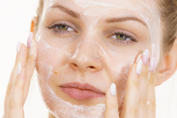 Young woman applying cream cosmetic, mask moisturizing to her face. Beauty treatment. Skincare. - Foto, Bild