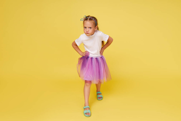 Portrait of offended little toddler girl child over yellow background. Looking at camera. Advertising childrens products. - Foto, afbeelding