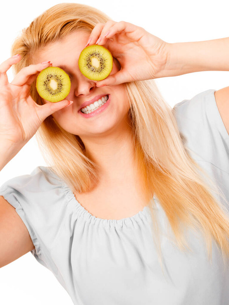 Healthy diet, refreshing food full of vitamins. Woman holding sweet delicious green kiwi fruit, pretending it is eyeglasses. - Foto, imagen