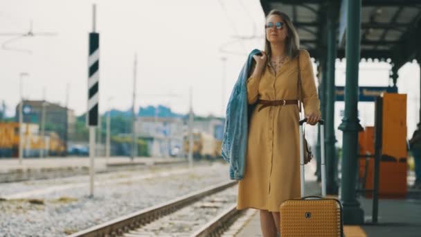 Woman with travel suitcase is waiting for a train. - Materiał filmowy, wideo