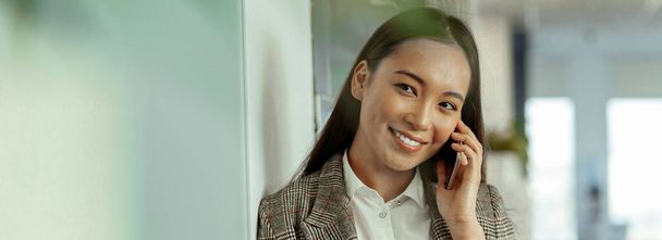 Asian business woman making a phone call and smiling. High quality photo - Foto, Imagem
