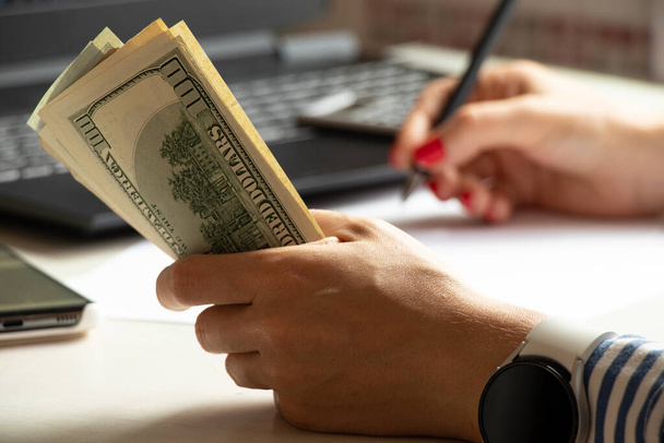 Доллары в руках женщины за столом, деньги и экономика, успех и прибыль - Фото, изображение