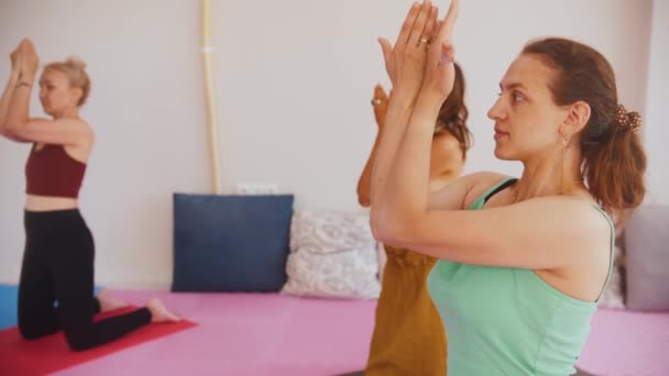 Three women on yoga mats doing exercises for their back and spine. Mid shot - Video, Çekim