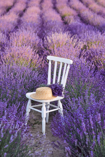 sedia bianca con bouquet di lavanda e cappello di paglia a fiori di lavanda bella fioritura. Viaggi, natura, estate, agricoltura concetto - Foto, immagini