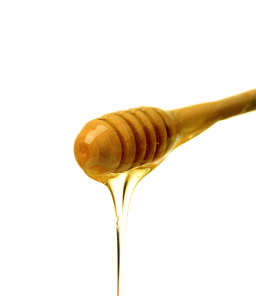 Honey dripping from a wooden honey dipper - 写真・画像
