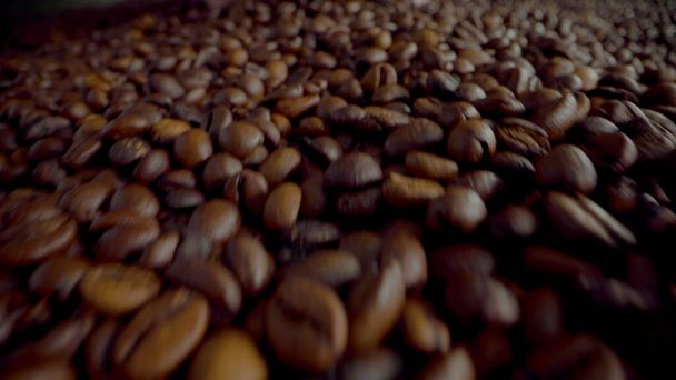 Closeup fresh coffee beans taken in unknown man hands. Camera going through large heap roasted aromatic seeds. Unrecognizable agriculturist holding fragrant crop coffee grains in full palms.  - Photo, Image