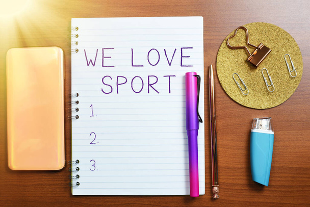 Text showing inspiration We Love Sport, Word Written on To like a lot practicing sports athletic activities work out Notebook With Important Message On Desk With Office Supplies. - Photo, image