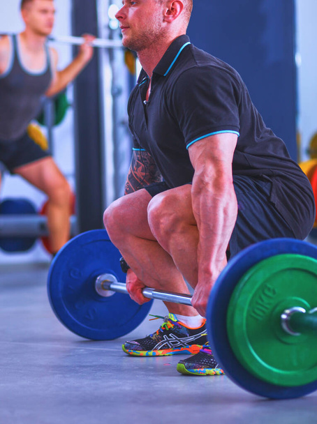 Bodybuilder standing with barbell in gym . - Foto, Bild