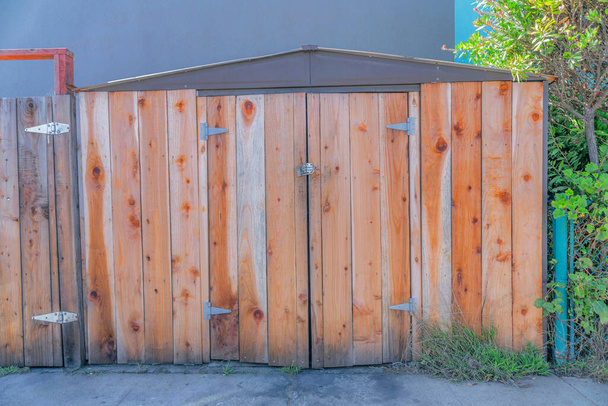 Tool shed with wood planks walls and double door in San Francisco, California. Exterior of a shed with side-hinged double doors against the wall and plants on the side and back. - Foto, Imagem