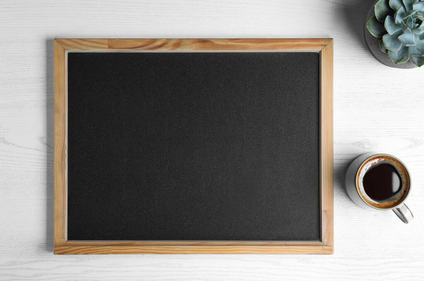Clean small chalkboard, coffee and plant on white wooden table, flat lay - Foto, Imagem
