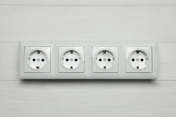 Modern plastic power socket on white wooden table, top view - Фото, изображение