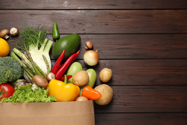 Fresh vegetables in paper shopping bag on wooden table, flat lay. Space for text - Foto, Imagem